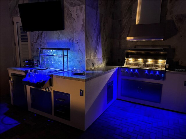 bar featuring ventilation hood, stainless steel counters, and decorative backsplash