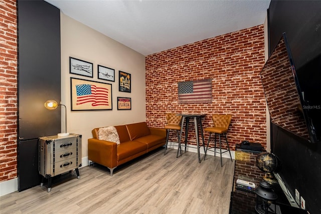 living room with light hardwood / wood-style floors and brick wall