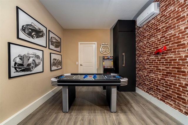 rec room featuring hardwood / wood-style flooring, brick wall, and a wall unit AC