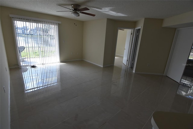 tiled empty room featuring ceiling fan and a textured ceiling