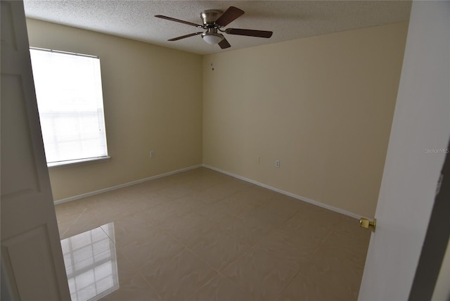 unfurnished room with ceiling fan and a textured ceiling