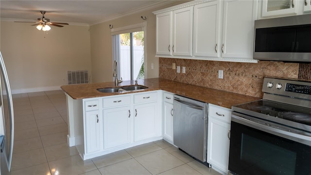 kitchen featuring kitchen peninsula, ornamental molding, stainless steel appliances, sink, and white cabinets