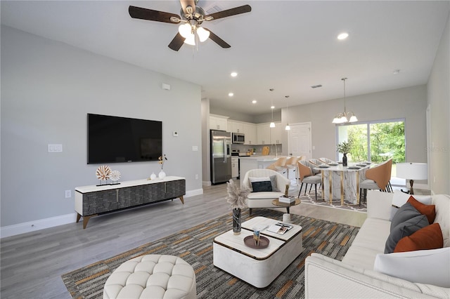 living room with wood-type flooring and ceiling fan with notable chandelier