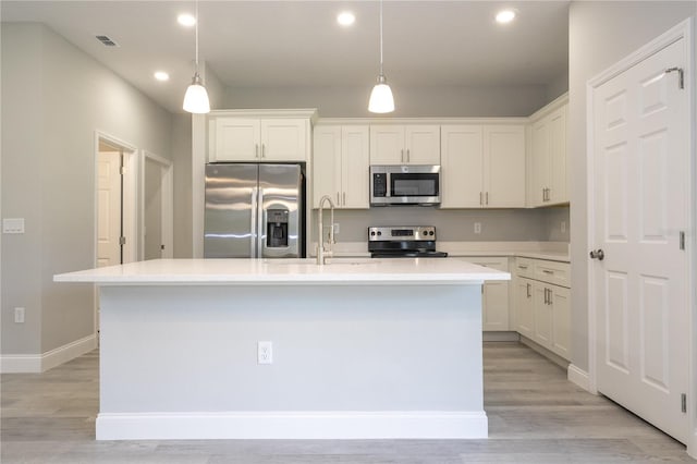 kitchen featuring white cabinetry, an island with sink, light hardwood / wood-style floors, and appliances with stainless steel finishes