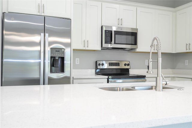 kitchen with light stone countertops, stainless steel appliances, and white cabinetry