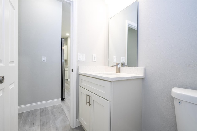 bathroom with hardwood / wood-style flooring, vanity, and toilet