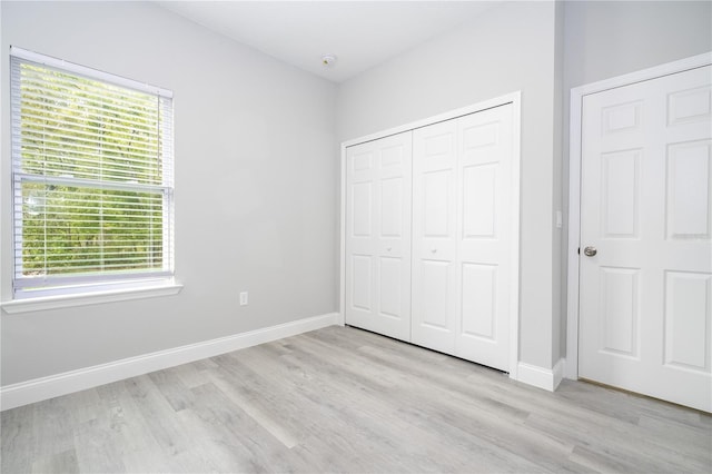 unfurnished bedroom featuring a closet, light wood-type flooring, and multiple windows