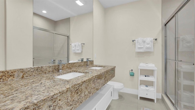 bathroom featuring tile patterned floors, vanity, toilet, and a shower with shower door