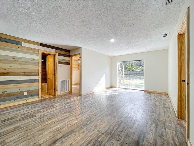 spare room with wooden walls, hardwood / wood-style floors, and a textured ceiling