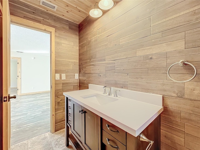 bathroom featuring wooden walls, tile patterned flooring, and vanity