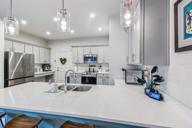 kitchen featuring decorative light fixtures, gray cabinets, a kitchen bar, kitchen peninsula, and appliances with stainless steel finishes