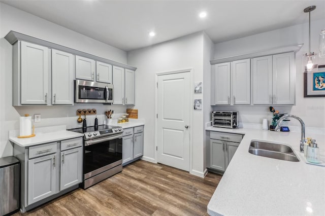 2920 Oak Park Way Apt A, Orlando, FL 32822 - kitchen with stainless steel appliances, gray cabinets, light countertops, dark wood finished floors, and hanging light fixtures