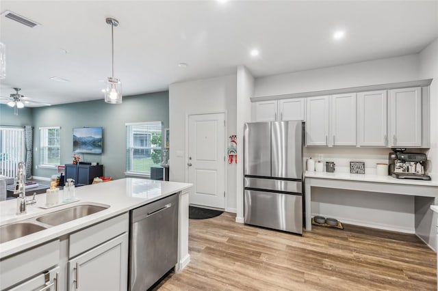 kitchen featuring ceiling fan, pendant lighting, sink, light wood-type flooring, and stainless steel appliances