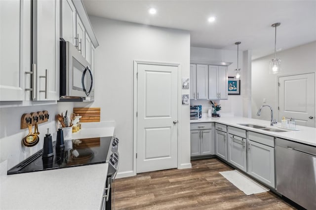 kitchen with appliances with stainless steel finishes, gray cabinetry, dark hardwood / wood-style flooring, hanging light fixtures, and sink