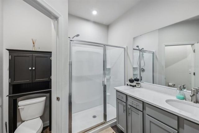 bathroom featuring a shower with shower door, vanity, and toilet