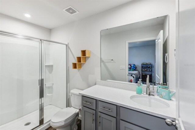 bathroom with toilet, a shower with door, and vanity