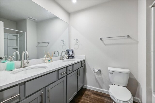 bathroom with toilet, vanity, wood-type flooring, and a shower