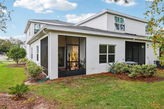 rear view of house featuring a sunroom, a lawn, and central AC