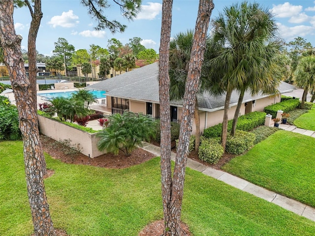 view of front of house with a front lawn and a community pool