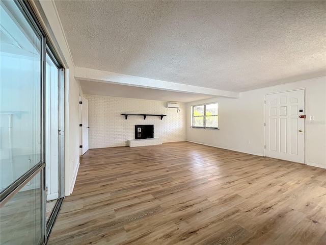 unfurnished living room with hardwood / wood-style flooring, a brick fireplace, a wall mounted AC, and brick wall