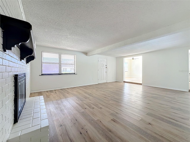 unfurnished living room with a fireplace, a textured ceiling, and light hardwood / wood-style flooring