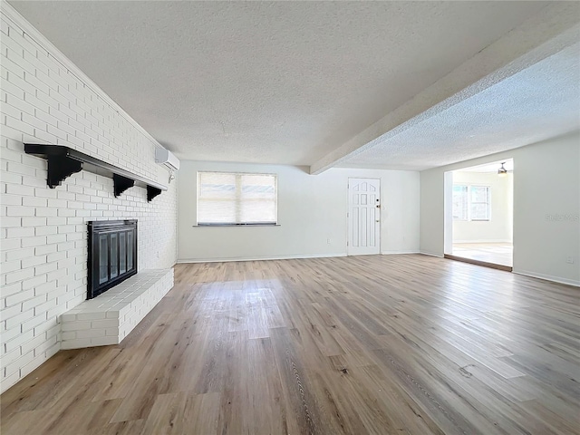 unfurnished living room featuring a fireplace, hardwood / wood-style floors, a healthy amount of sunlight, and a textured ceiling