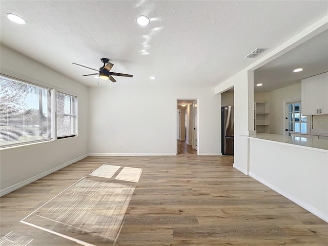 unfurnished living room featuring a textured ceiling, light hardwood / wood-style floors, and ceiling fan