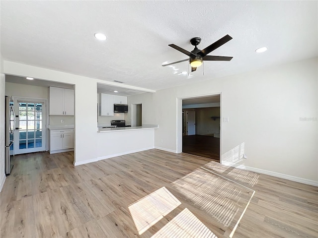 unfurnished living room with ceiling fan, a textured ceiling, and light wood-type flooring