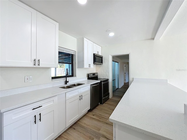 kitchen featuring stainless steel appliances, white cabinetry, sink, and light hardwood / wood-style flooring