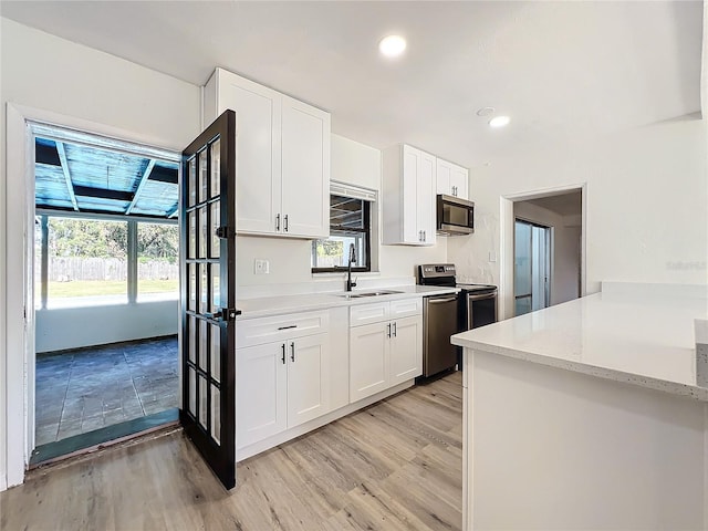 kitchen with white cabinetry, sink, light hardwood / wood-style floors, and appliances with stainless steel finishes