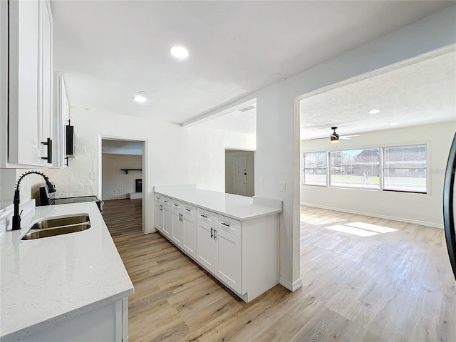 kitchen with white cabinets, light hardwood / wood-style flooring, ceiling fan, and sink