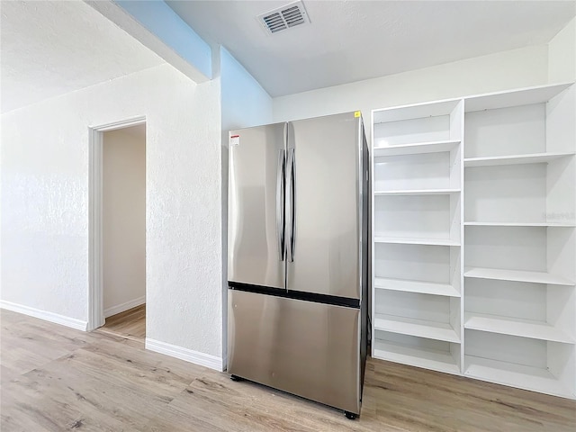 interior space with stainless steel fridge and light hardwood / wood-style flooring