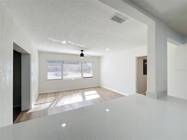 unfurnished room featuring a textured ceiling, light wood-type flooring, and ceiling fan