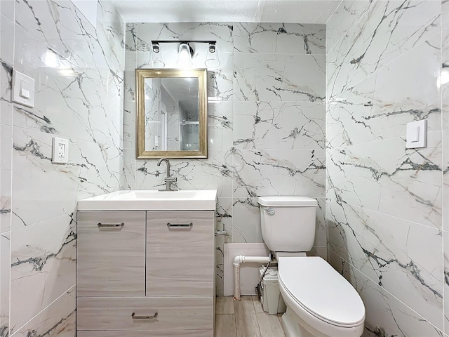 bathroom featuring vanity, tile walls, and toilet