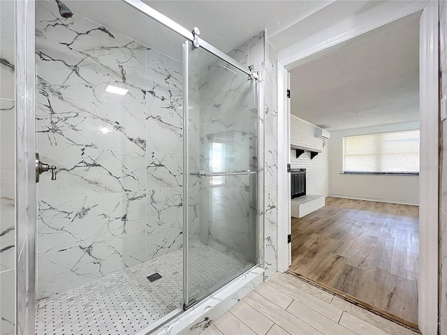 bathroom featuring a wall unit AC, a fireplace, and a shower with shower door