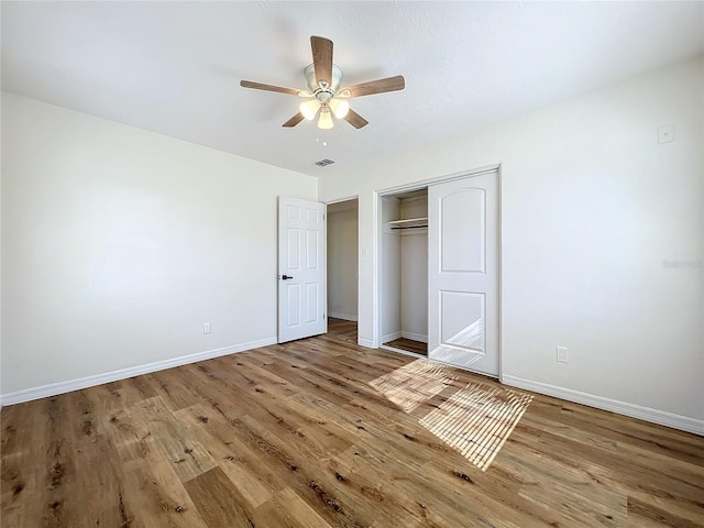 unfurnished bedroom with ceiling fan, wood-type flooring, and a closet