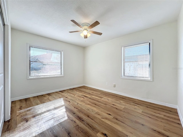 unfurnished room featuring ceiling fan, a textured ceiling, a wealth of natural light, and light hardwood / wood-style flooring