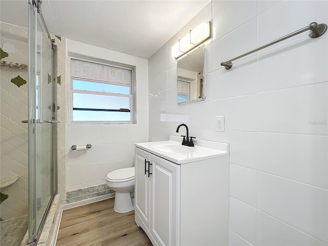 bathroom with vanity, hardwood / wood-style flooring, toilet, tile walls, and walk in shower