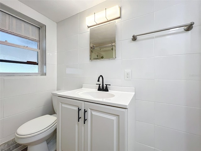 bathroom with vanity, toilet, and tile walls