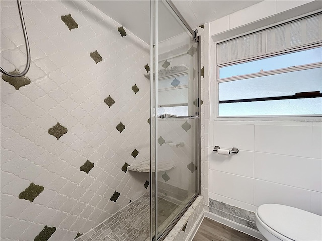 bathroom with hardwood / wood-style flooring, toilet, and a shower with door