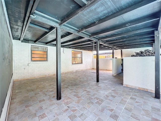 basement featuring a baseboard radiator, water heater, and brick wall