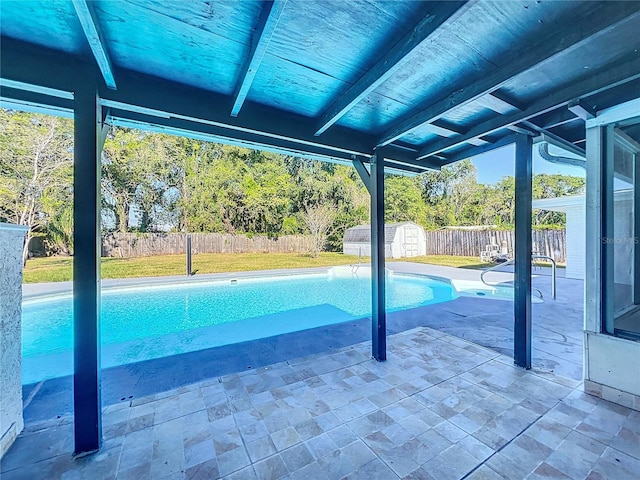 view of pool with a lawn and a storage shed