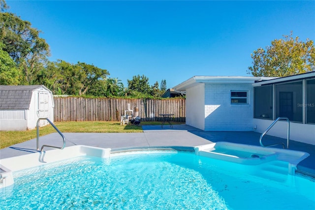 view of swimming pool featuring a yard, a storage shed, a patio area, and a sunroom