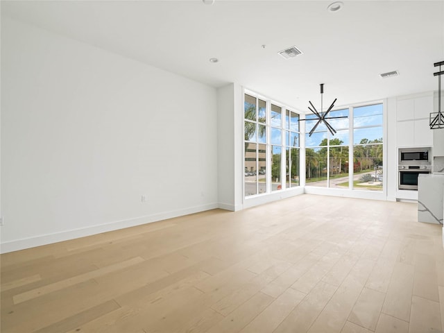 unfurnished living room featuring light hardwood / wood-style floors, floor to ceiling windows, and an inviting chandelier