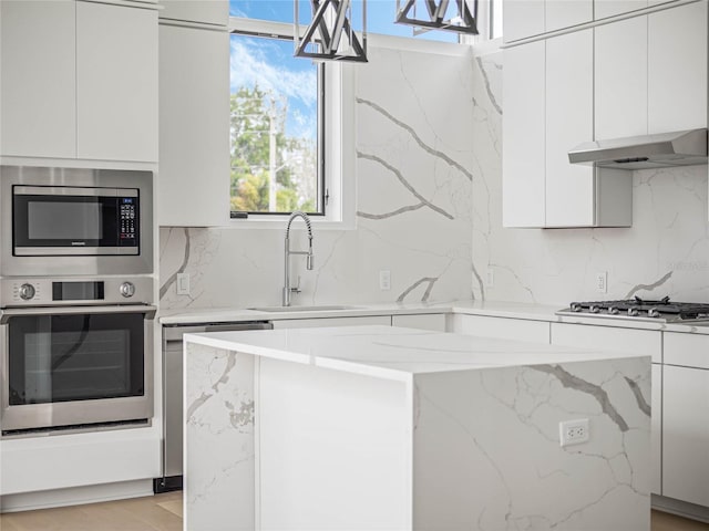 kitchen with backsplash, white cabinets, hanging light fixtures, sink, and appliances with stainless steel finishes