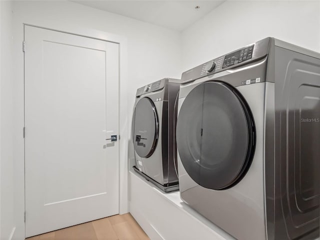 laundry area featuring washing machine and dryer and light hardwood / wood-style flooring