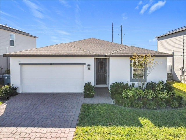 view of front of home with central AC unit, a garage, and a front lawn