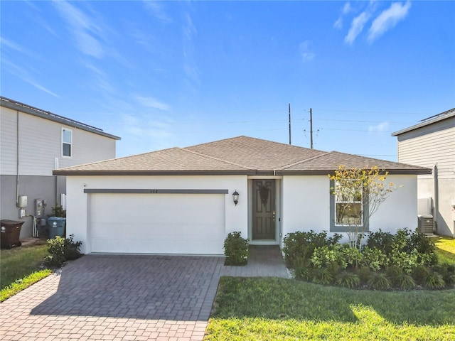 view of front of property featuring central AC unit, a garage, and a front yard