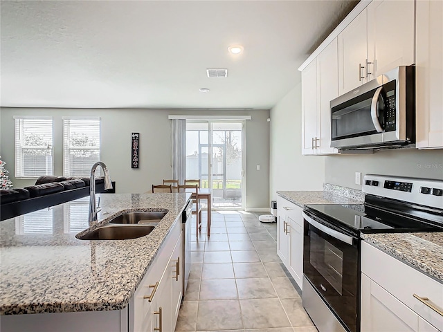 kitchen with a healthy amount of sunlight, light stone countertops, sink, and appliances with stainless steel finishes