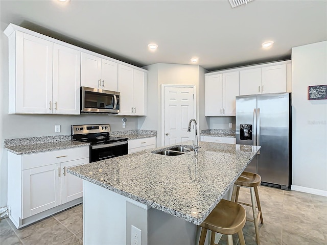 kitchen featuring white cabinets, stainless steel appliances, a center island with sink, and sink